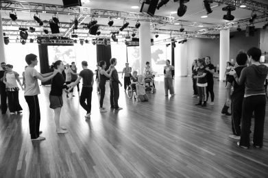 Studio full of dancers, massaging each others shoulders.