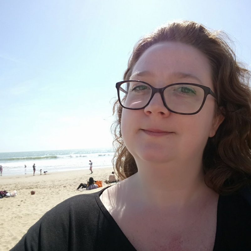 Lucy White. A white woman with red hair and glasses